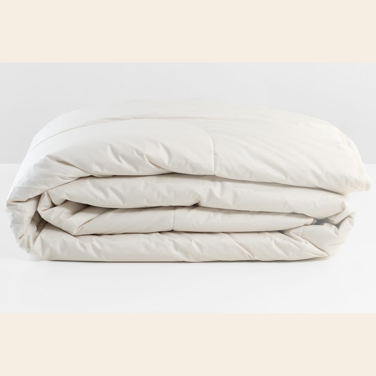 Alpaca duvet folded, showing the undyed organic cotton shell and the hand-closed edge