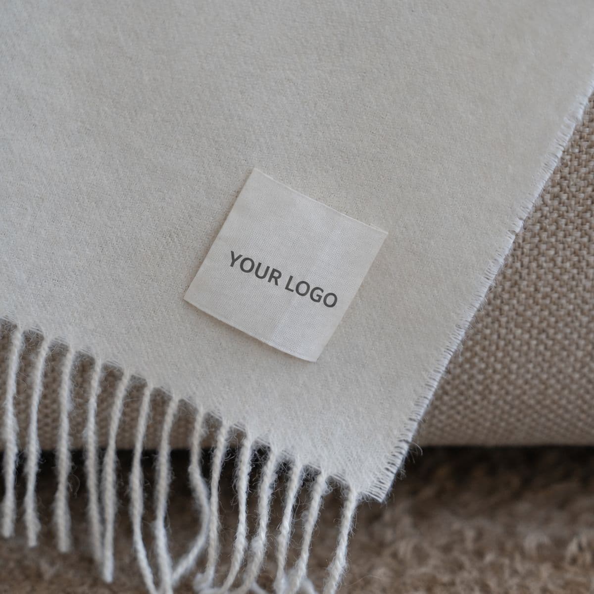 Baby Alpaca throw with the customer's own logo on a sewn cotton label, beside the fringed edge